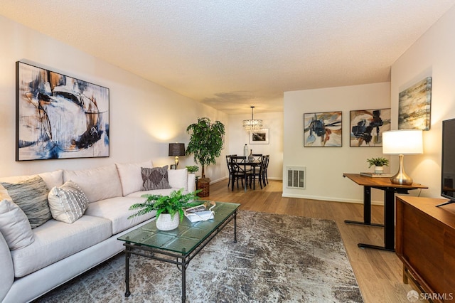 living room featuring hardwood / wood-style flooring, a chandelier, and a textured ceiling