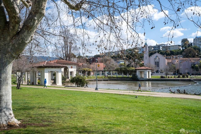 view of property's community with a water view and a lawn