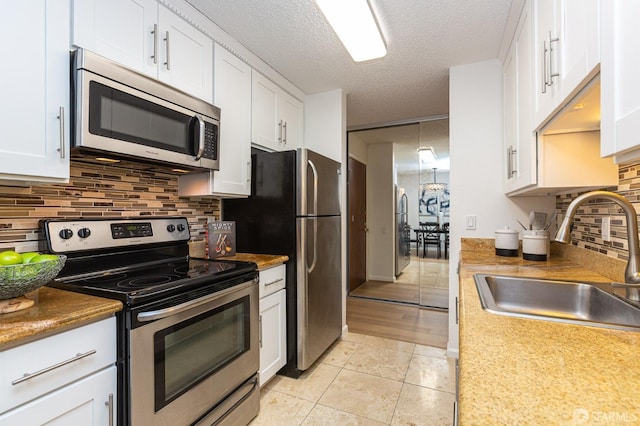 kitchen with sink, light tile patterned flooring, white cabinets, and appliances with stainless steel finishes