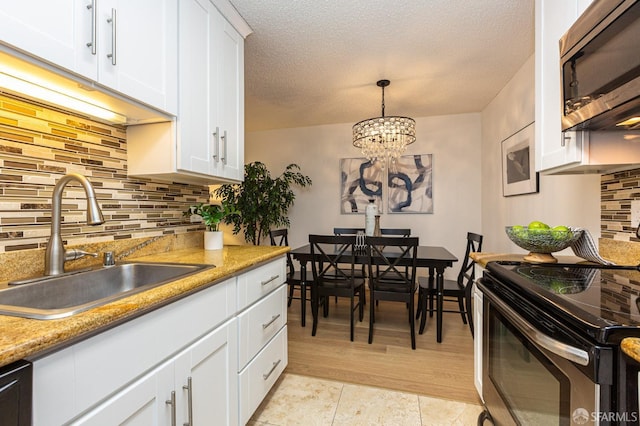 kitchen featuring pendant lighting, sink, appliances with stainless steel finishes, white cabinetry, and a textured ceiling