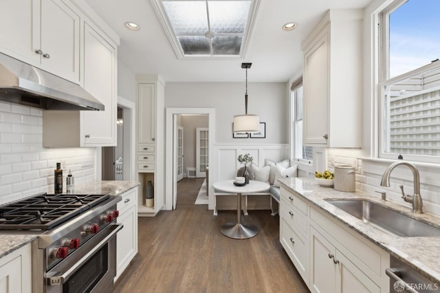 kitchen featuring dark wood-style floors, a sink, white cabinets, under cabinet range hood, and appliances with stainless steel finishes