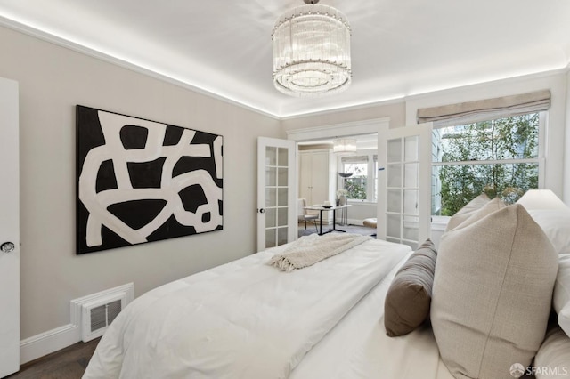 bedroom with a chandelier, visible vents, french doors, and baseboards