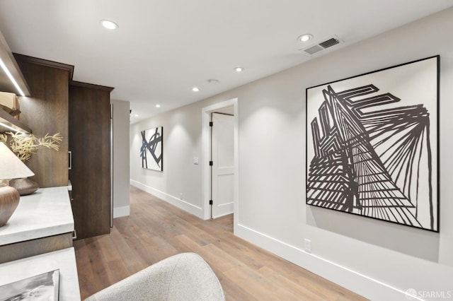 hall featuring visible vents, recessed lighting, baseboards, and light wood-style floors