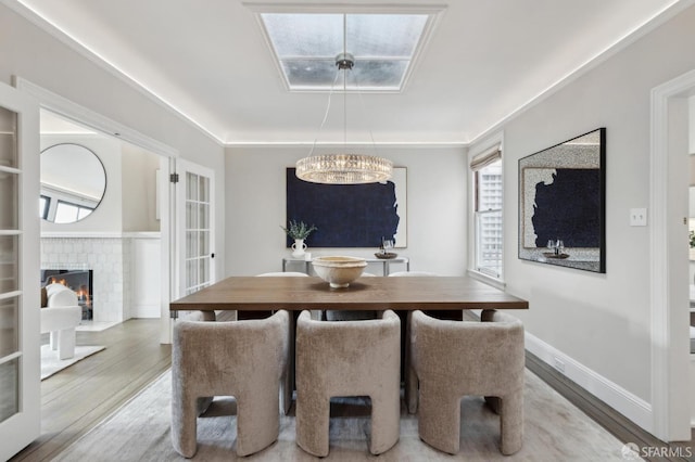 dining area featuring baseboards, a brick fireplace, and wood finished floors