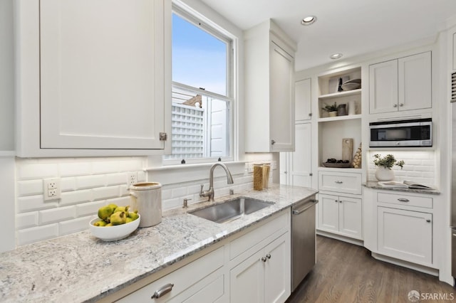 kitchen featuring open shelves, a sink, decorative backsplash, appliances with stainless steel finishes, and white cabinetry