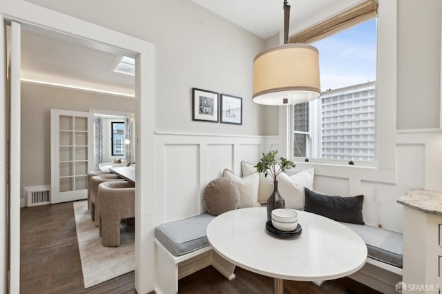 dining space featuring visible vents, a wainscoted wall, wood finished floors, breakfast area, and a decorative wall