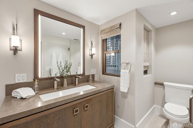 bathroom with vanity, toilet, recessed lighting, and baseboards