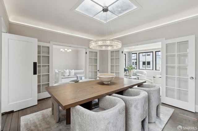 dining room with wood finished floors, a skylight, french doors, and a chandelier