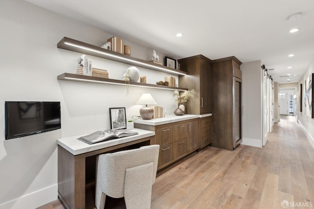 office area featuring a barn door, recessed lighting, baseboards, and light wood finished floors