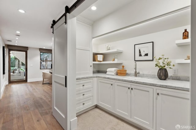 bar featuring recessed lighting, light wood-style flooring, a barn door, and a sink