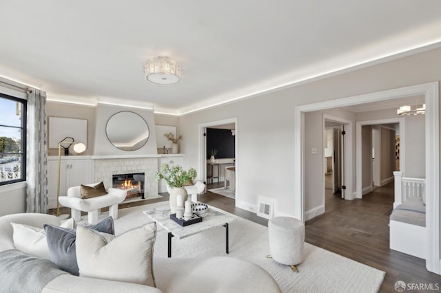 living room with visible vents, baseboards, a chandelier, a tile fireplace, and dark wood-style flooring