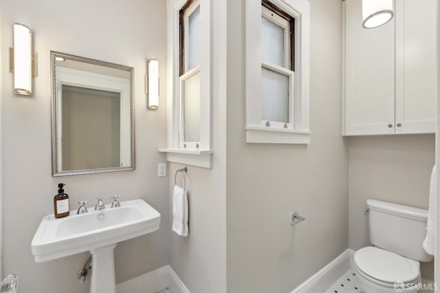 bathroom with toilet, baseboards, and a sink