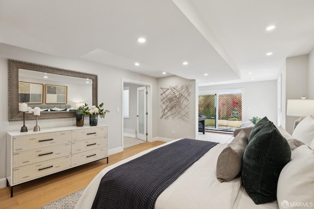 bedroom with access to exterior, ensuite bathroom, and light wood-type flooring