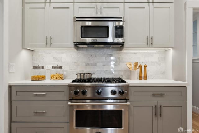 kitchen with gray cabinetry, decorative backsplash, and appliances with stainless steel finishes