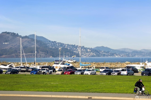 view of car parking with a yard and a water and mountain view