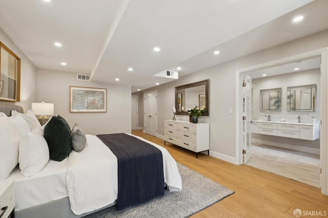 bedroom featuring ensuite bathroom, sink, and light hardwood / wood-style flooring