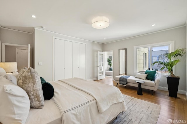 bedroom featuring french doors, wood-type flooring, and ornamental molding