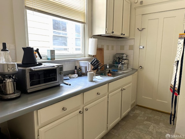 kitchen featuring tasteful backsplash, white cabinetry, and sink