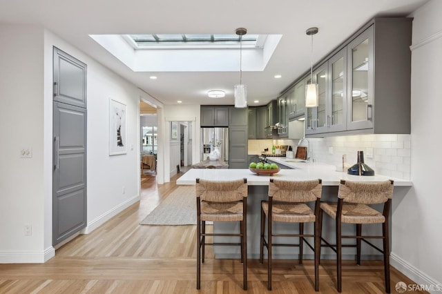 kitchen featuring a skylight, stainless steel fridge, backsplash, and kitchen peninsula