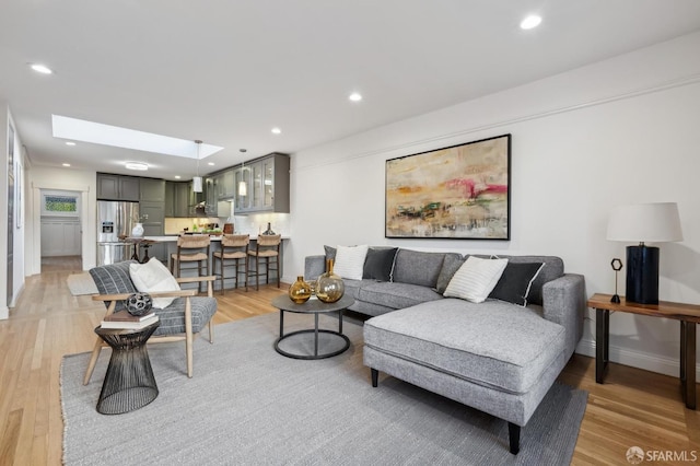 living room featuring a skylight and light wood-type flooring