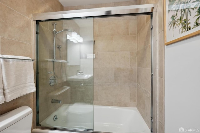 bathroom featuring toilet and combined bath / shower with glass door