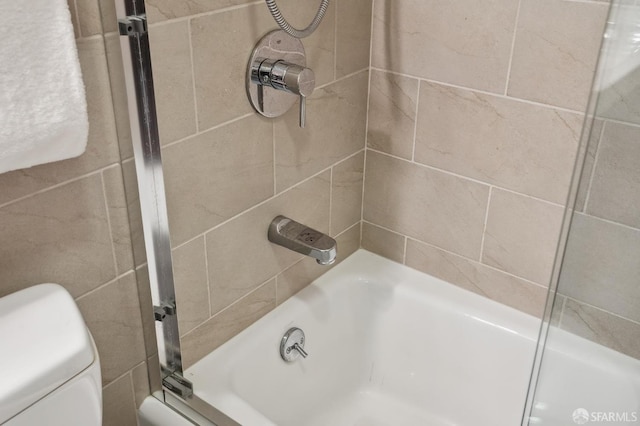 bathroom featuring bath / shower combo with glass door and toilet