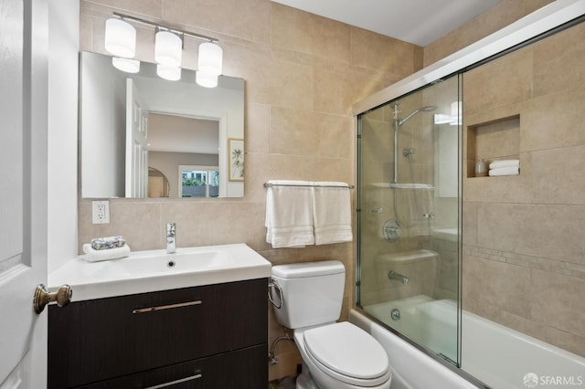 full bathroom with toilet, tile walls, vanity, enclosed tub / shower combo, and backsplash