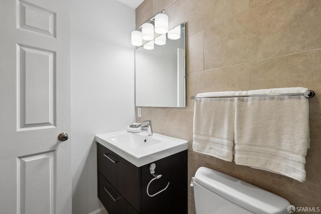 bathroom featuring vanity, tile walls, and toilet