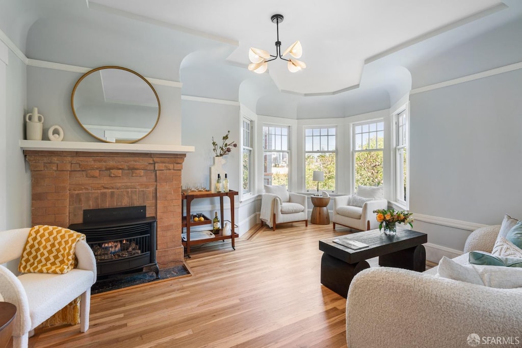 living room with a brick fireplace, hardwood / wood-style floors, and a chandelier