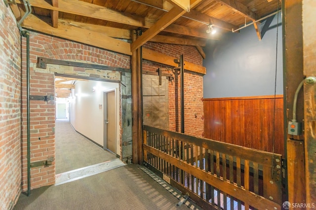 hall featuring wood ceiling, beam ceiling, carpet floors, brick wall, and wood walls