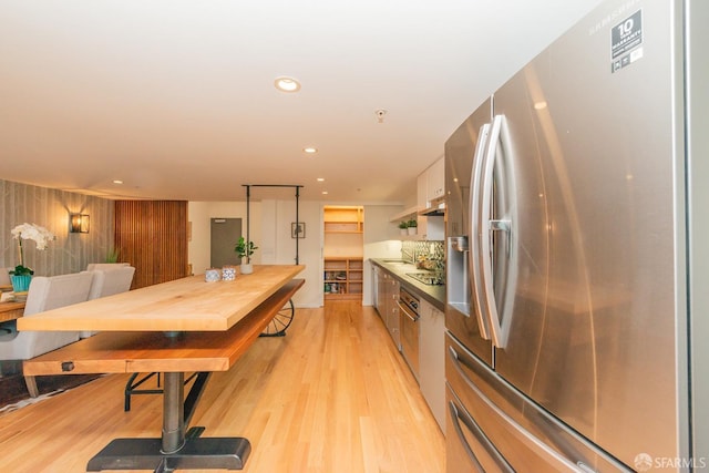 kitchen featuring stainless steel refrigerator with ice dispenser, sink, white cabinetry, light hardwood / wood-style flooring, and black electric cooktop