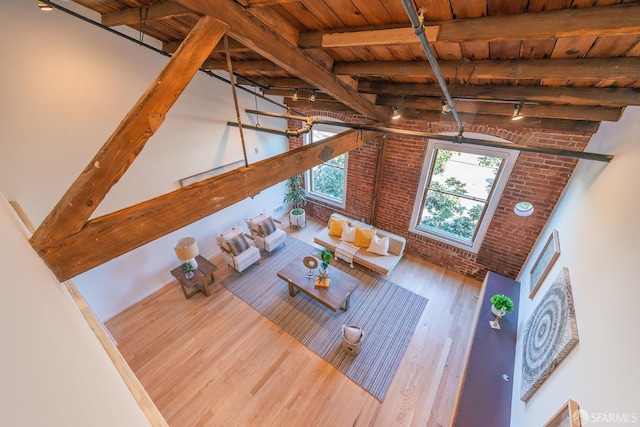 unfurnished living room with hardwood / wood-style flooring, brick wall, wood ceiling, and beam ceiling