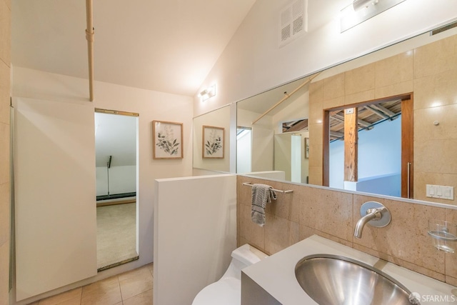 bathroom featuring tile patterned floors, lofted ceiling, tasteful backsplash, tile walls, and vanity