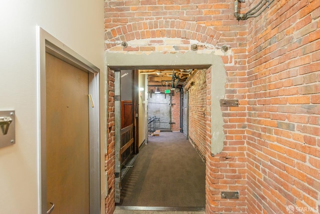 hall featuring brick wall and carpet floors