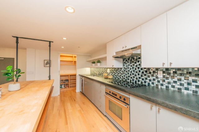 kitchen featuring backsplash, white cabinets, stainless steel oven, black electric cooktop, and light hardwood / wood-style flooring