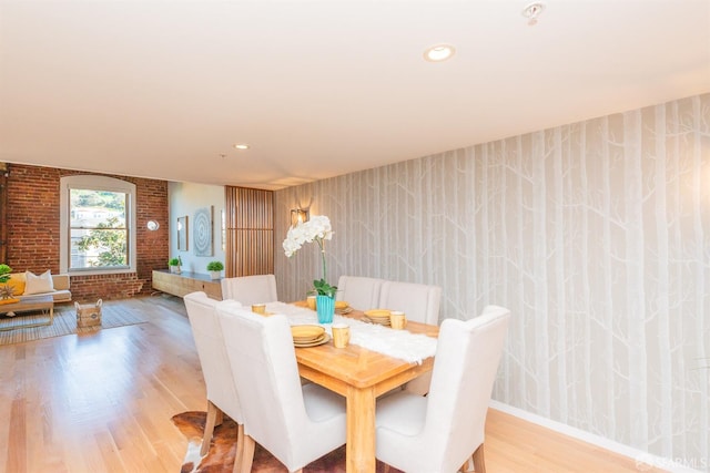 dining space with brick wall and wood-type flooring