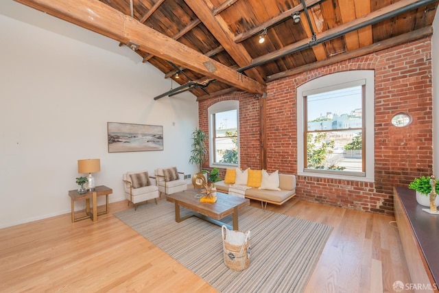 unfurnished living room featuring track lighting, lofted ceiling with beams, light hardwood / wood-style floors, brick wall, and wooden ceiling