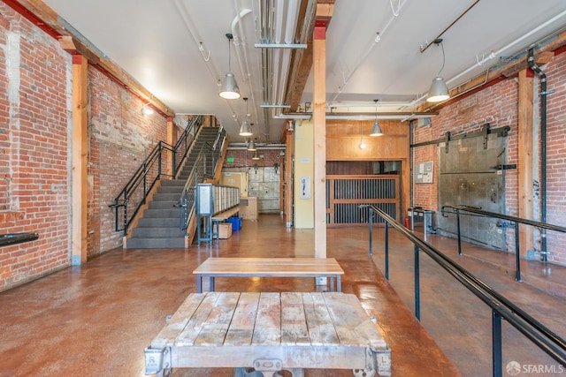 interior space with a towering ceiling, concrete flooring, a barn door, and brick wall