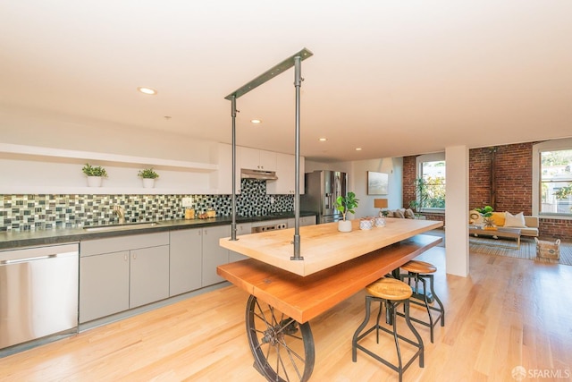 kitchen featuring stainless steel appliances, sink, backsplash, and light hardwood / wood-style flooring