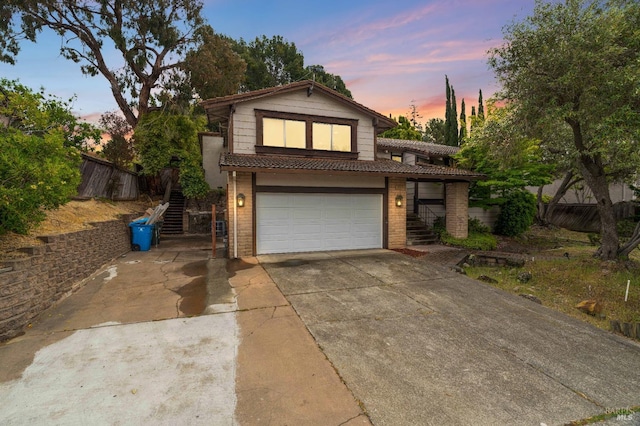 view of front of property with stairs, a garage, brick siding, and concrete driveway