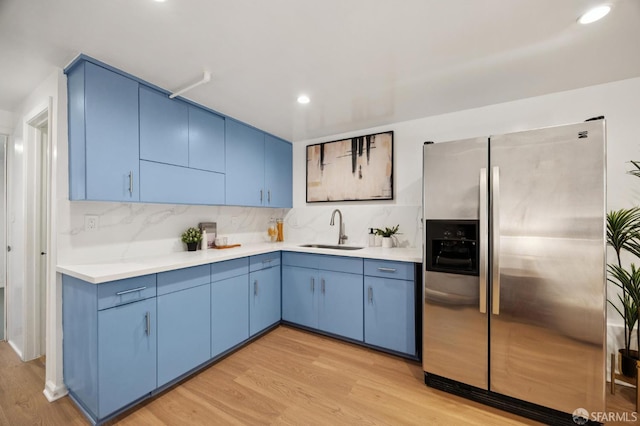 67 Rome St, San Francisco, CA 94112 - kitchen with stainless steel refrigerator with ice dispenser, blue cabinetry, light wood finished floors, light countertops, and backsplash