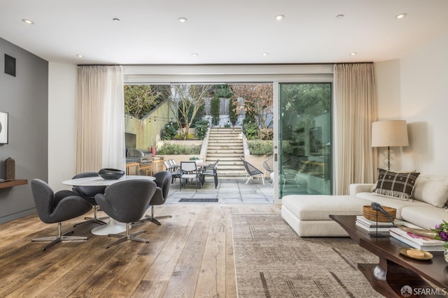 living area with recessed lighting, wood-type flooring, and a healthy amount of sunlight