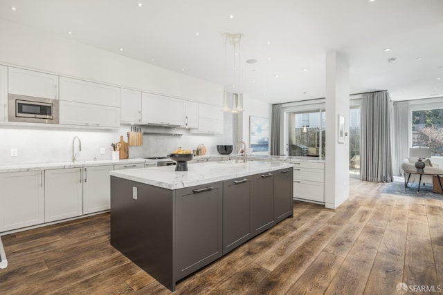 kitchen featuring a sink, dark wood-style floors, white cabinetry, and stainless steel microwave