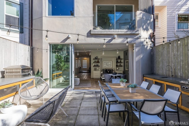 view of patio / terrace featuring a sink, outdoor dining area, and fence