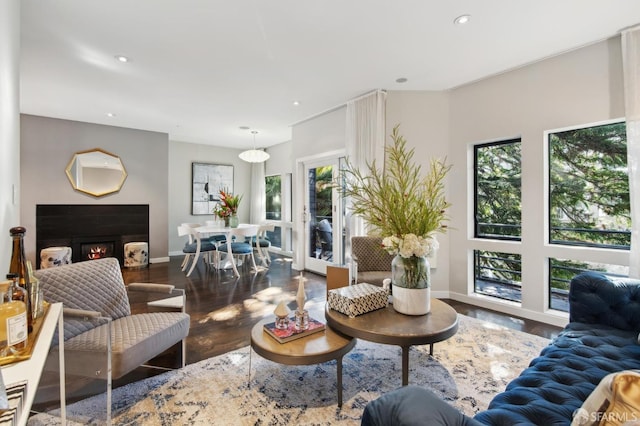 living room with baseboards, a lit fireplace, dark wood-type flooring, and recessed lighting