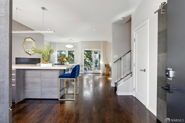 kitchen featuring light countertops, hanging light fixtures, dark wood-type flooring, and a kitchen breakfast bar