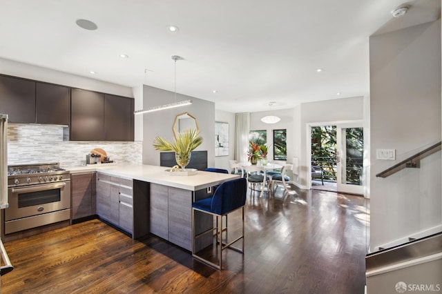 kitchen with stainless steel stove, a peninsula, a kitchen breakfast bar, open floor plan, and light countertops