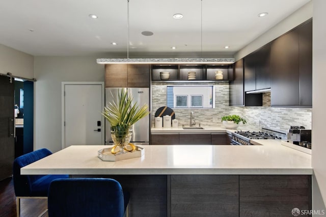 kitchen featuring a barn door, a breakfast bar area, light countertops, appliances with stainless steel finishes, and pendant lighting