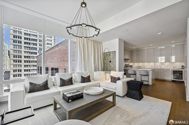 living room featuring light hardwood / wood-style flooring, wine cooler, and a chandelier