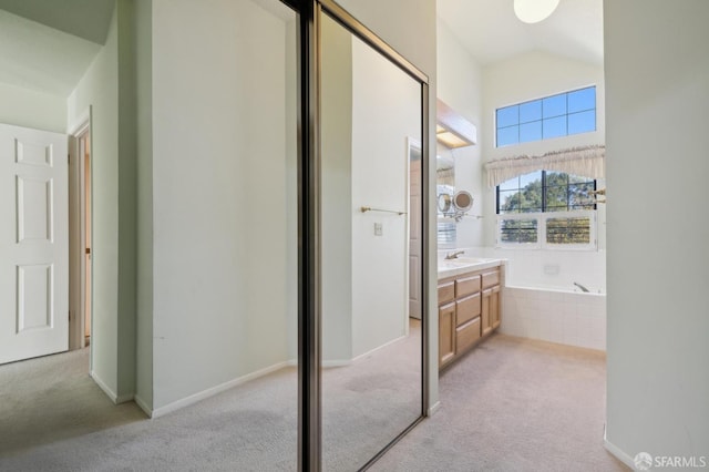 bathroom with vanity and tiled bath